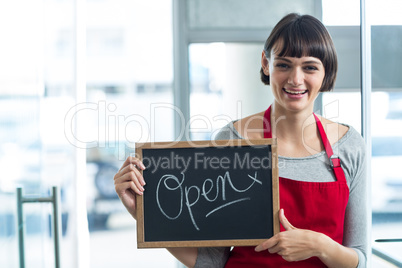 Smiling waitress showing slate with open sign