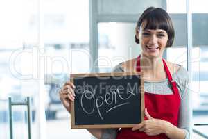 Smiling waitress showing slate with open sign