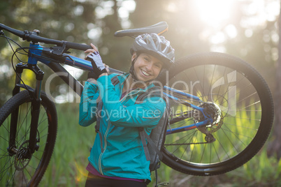 Portrait of female biker carrying mountain bike