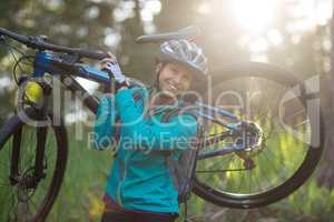 Portrait of female biker carrying mountain bike