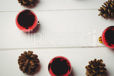 Red christmas bauble and pine cone on wooden table