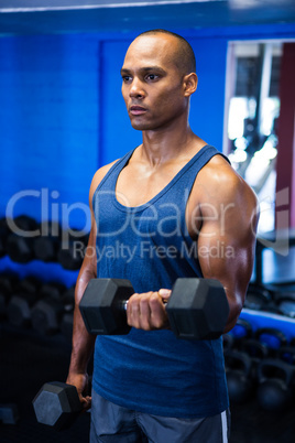 Muscular man exercising with dumbbells