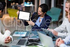 Businesswoman showing digital tablet to colleagues