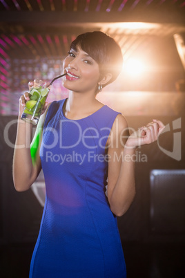 Young woman dancing on dance floor while having cocktail