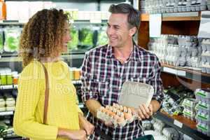 Man interacting with woman while holding egg carton