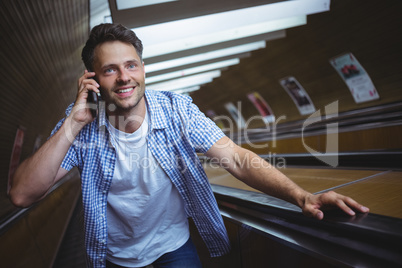 Handsome man talking on mobile phone on escalator