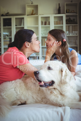 Mother and daughter sitting with pet dog in living room