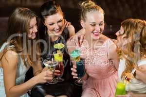 Female friends interacting with each other while having cocktail