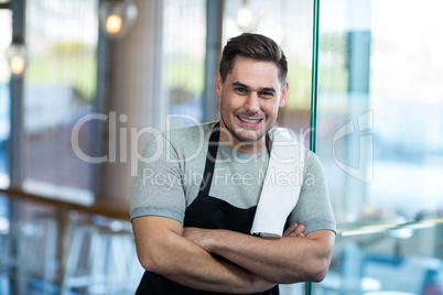 Smiling waiter leaning on glass door in cafÃ?Â©