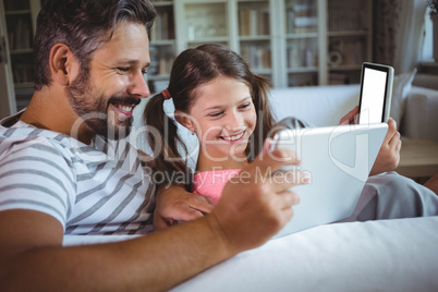 Happy father and daughter using digital tablet in living  room