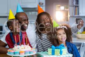 Family taking selfie with birthday cake