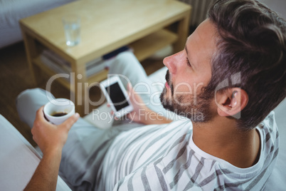 Father using phone while having coffee in living room