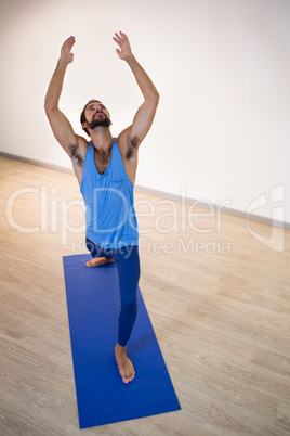 Man doing warrior pose on exercise mat