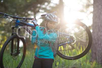 Female biker carrying mountain bike