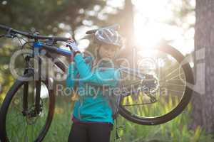 Female biker carrying mountain bike