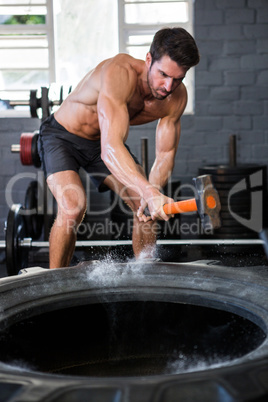Male athlete exercising with sledgehammer