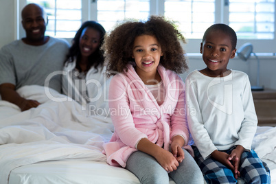 Children sitting on bed with parents in background