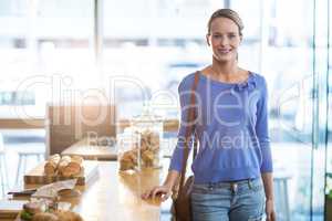 Portrait of woman standing beside counter