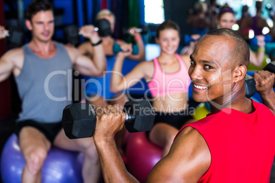 Portrait of smiling man holding dumbbell in gym