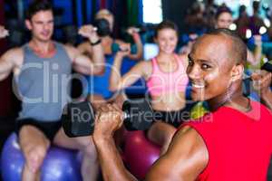 Portrait of smiling man holding dumbbell in gym