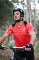 Male mountain biker with bicycle in the forest