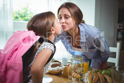 Mother and daughter kissing each other while having breakfast