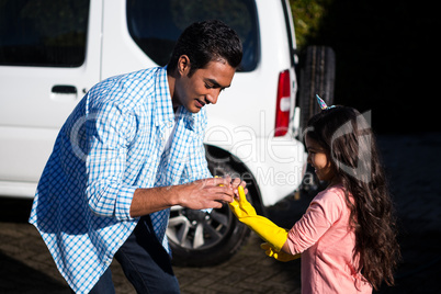 Father helping daughter to wear gloves