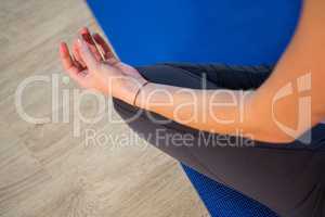 Mid section of woman doing yoga on exercise mat