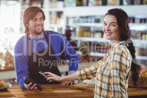 Woman paying bill through smartphone using NFC technology