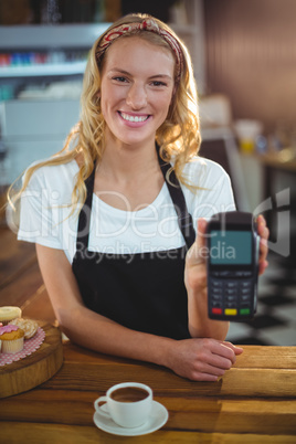 Portrait of smiling waitress holding credit card reader