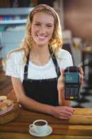 Portrait of smiling waitress holding credit card reader