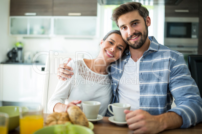 Portrait of couple sitting with arm around while having breakfast