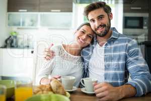 Portrait of couple sitting with arm around while having breakfast