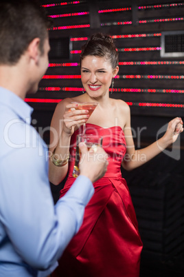 Smiling couple holding glass of beer and cocktail while dancing