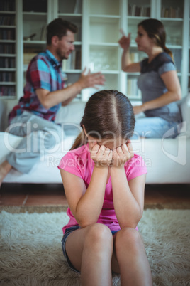 Sad girl crying while parents arguing in living room