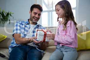 Father giving gift to daughter in the living room