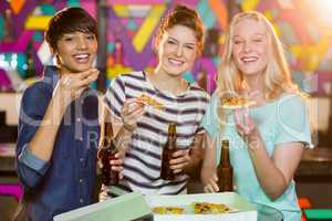 Three female friends having bottle of beer and pizza in party