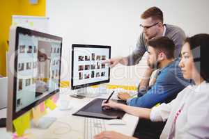 Executive using graphics tablet while colleagues discussing at creative office