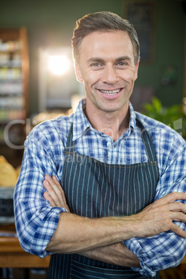 Portrait of smiling male staff standing with his hands crossed