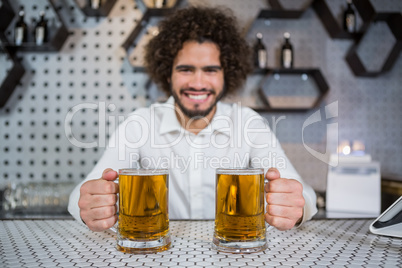 Bartender holding two glass of beer in bar counter