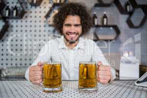 Bartender holding two glass of beer in bar counter