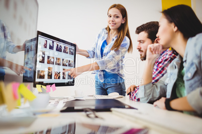 Smiling businesswoman showing computer screen to coworkers