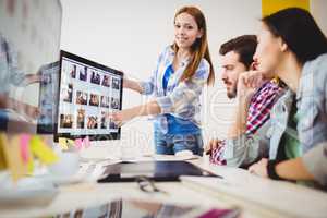 Smiling businesswoman showing computer screen to coworkers