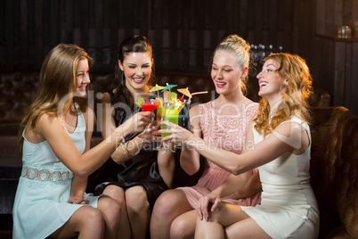 Female friends toasting glasses of cocktail in bar