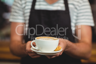 Mid section of waiter offering a cup of coffee