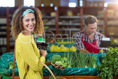 Smiling woman buying vegetables in organic section