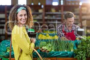 Smiling woman buying vegetables in organic section