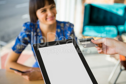 Hand holding a credit card next to the digital tablet in the coffee shop