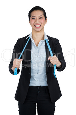 Businesswoman holding a measuring tape against white background