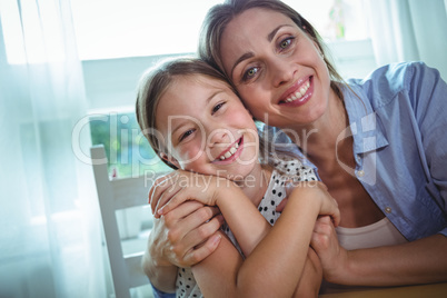 Happy mother and daughter embracing at home